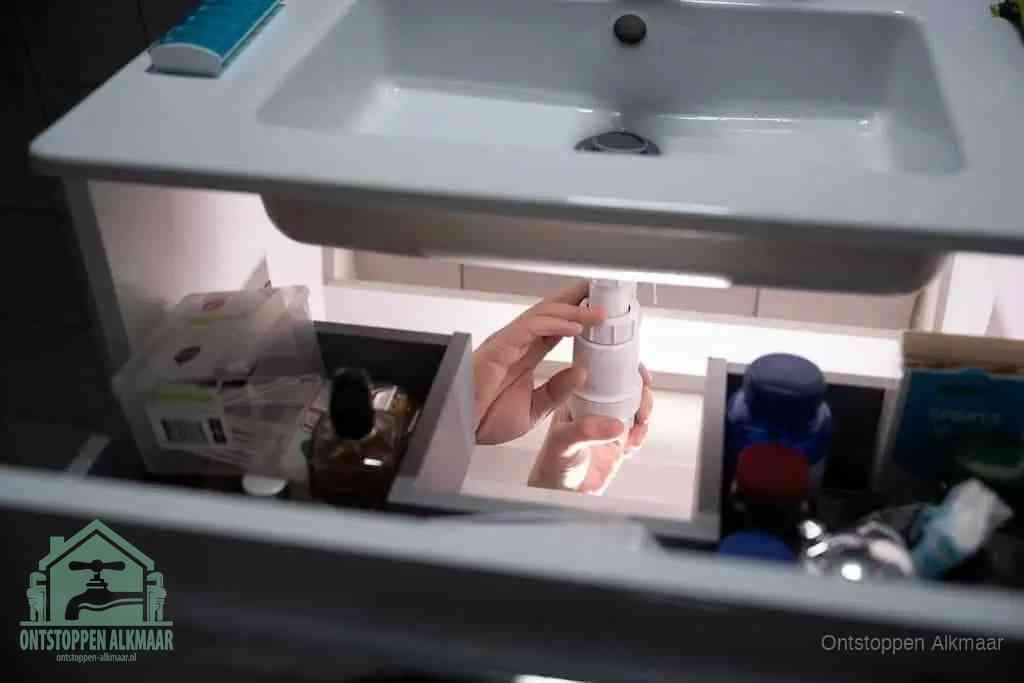 Een pompfles met zeep boven een wastafel, de heet water en afwasmiddel-methode om een vetprop in de afvoer los te maken in Alkmaar