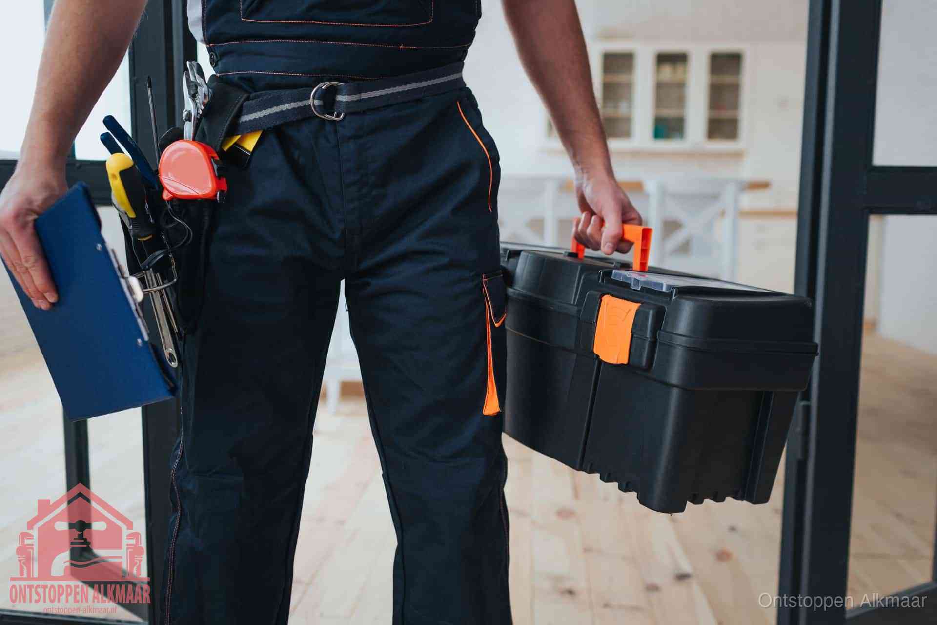 Een monteur met gereedschapsriem en klembord in een keuken, klaar om een transparante prijs voor het gootsteen ontstoppen in Alkmaar te geven