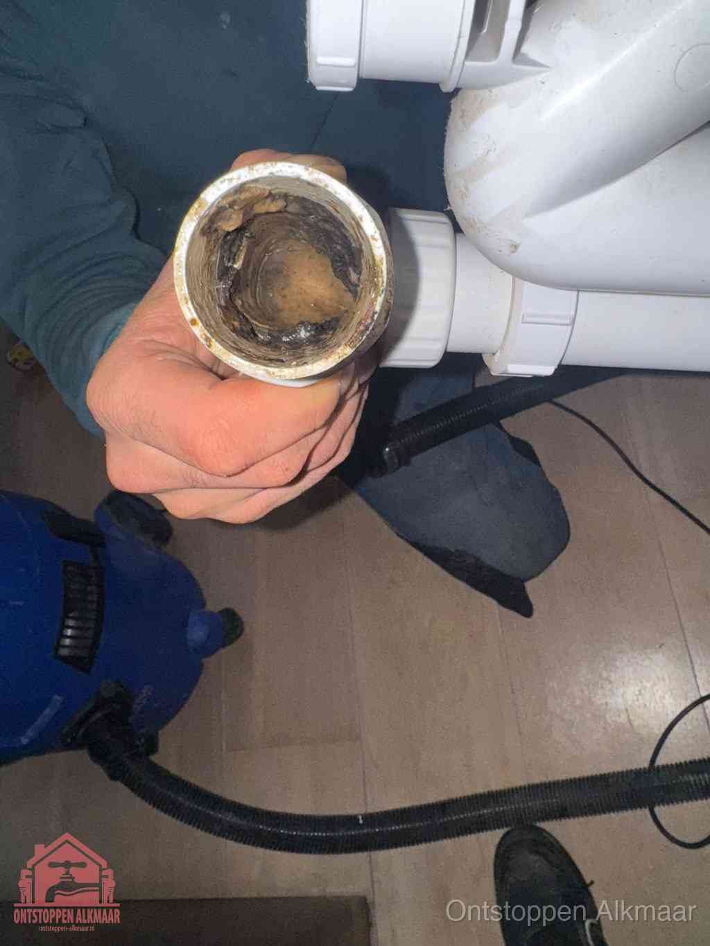 Een losgekoppelde afvoerbuis die van binnen volledig is dichtgeslibd met vet en aanslag, de meest voorkomende oorzaak van een verstopte gootsteen in Alkmaar