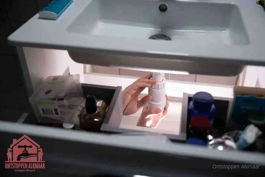 Een pompfles met zeep boven een wastafel in de toiletruimte, de warm water en afwasmiddel-methode om de wc te ontstoppen in Alkmaar