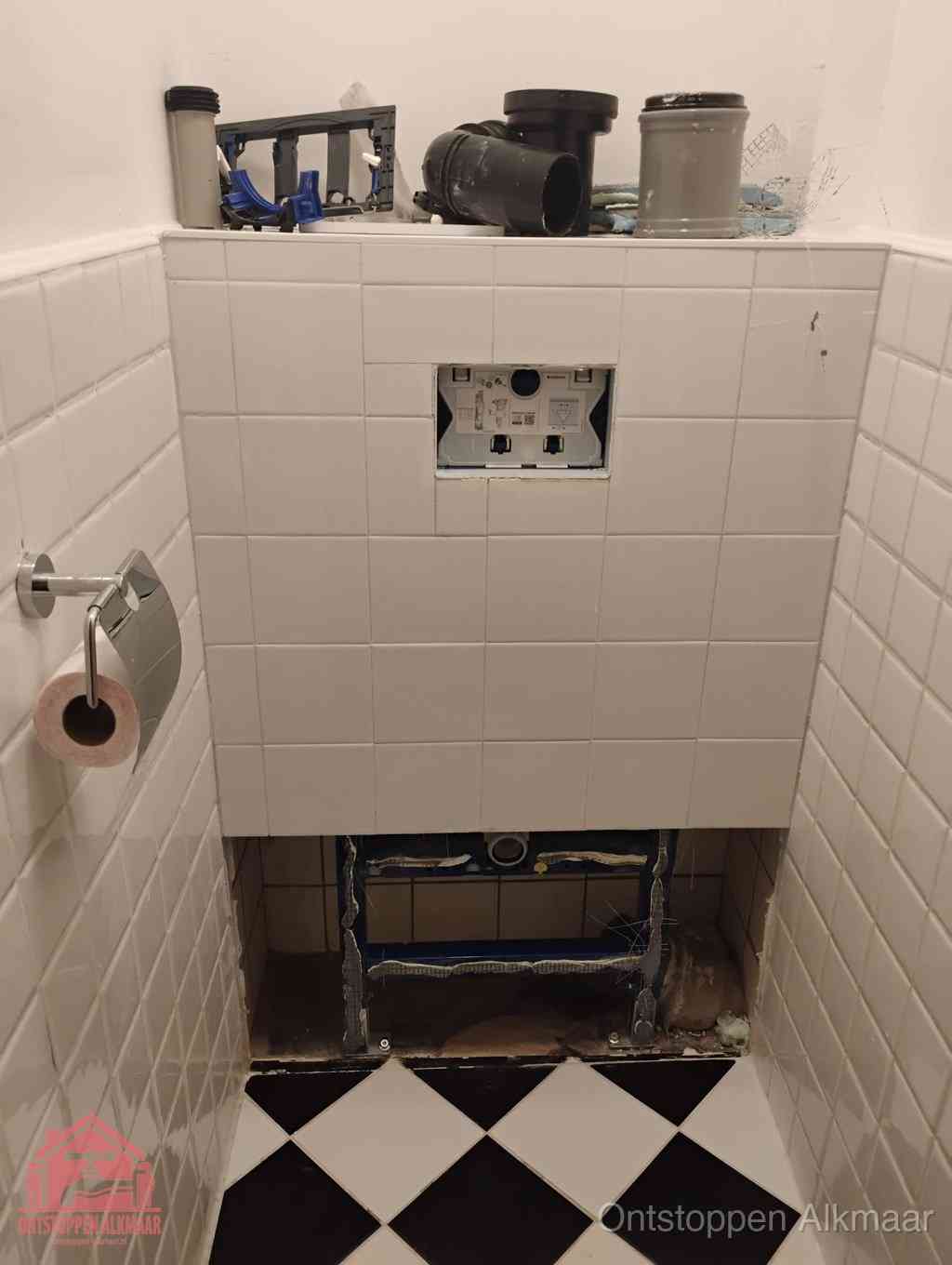Een toiletruimte waar het hangtoilet en de inbouwreservoir-onderdelen zijn vrijgelegd voor onderhoud, periodiek nazicht voorkomt een wc-verstopping in Alkmaar