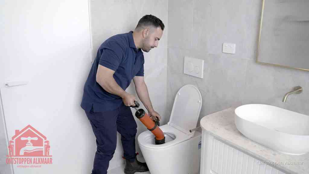 Een monteur gebruikt een handmatige perspomp (toiletontstopper) op een wandcloset tijdens het professioneel wc ontstoppen in Alkmaar